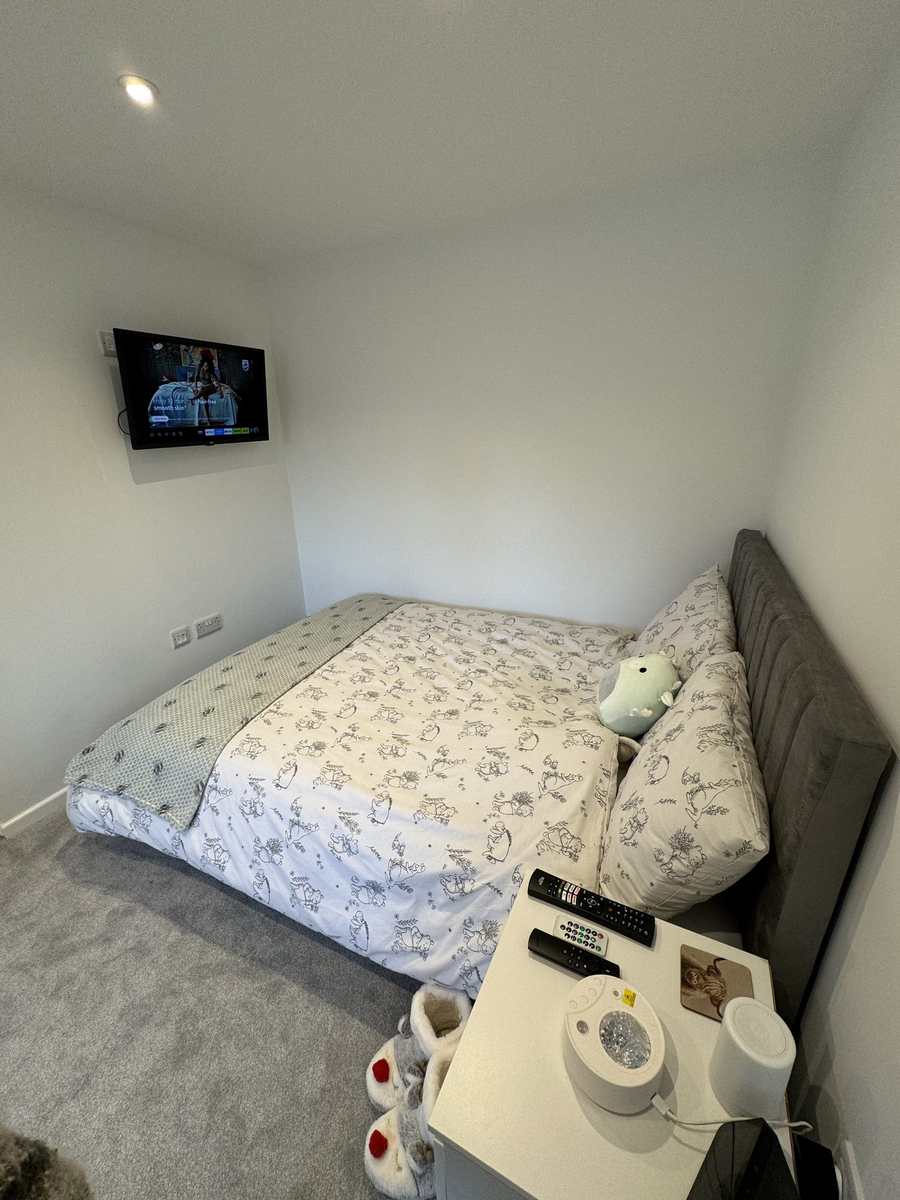 Converted garage in use as a bedroom, with a wall-mounted television