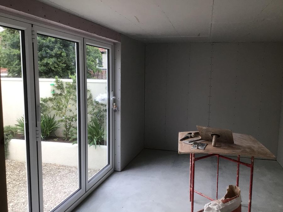 Garage conversion part-way through fit-out, with new glazed doors onto a courtyard garden