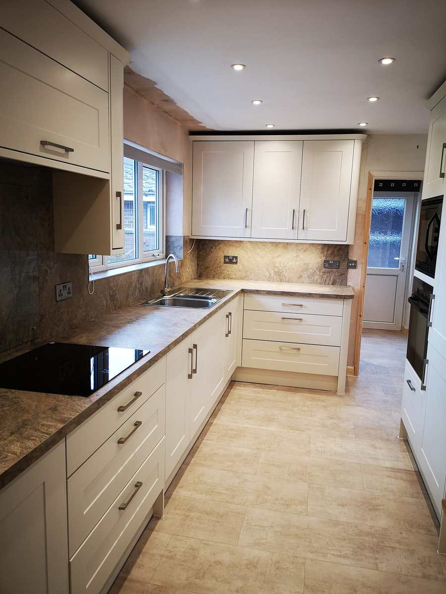 Finished kitchen with cream shaker units, a stone-effect worktop and integrated ovens