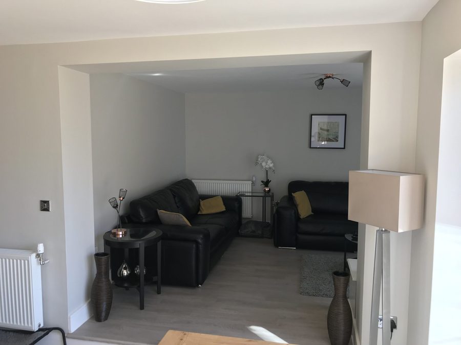 Finished open-plan living space with the dividing wall removed and a wide squared opening between the two rooms