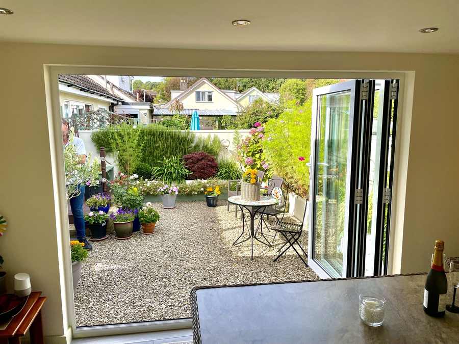 View from a converted garage through bifold doors onto a planted courtyard